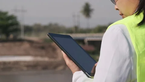 Female engineer uses a digital tablet to work outdoors at a construction site. Stock Footage 172412486