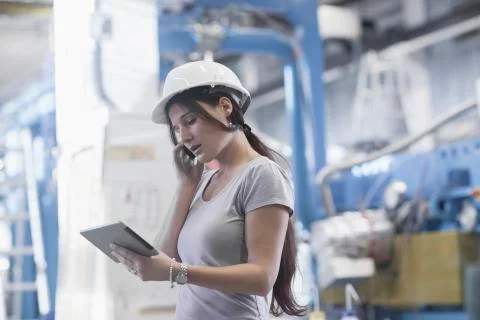 Female engineer using a digital tablet and mobile phone in an industrial plant Stock Photos
