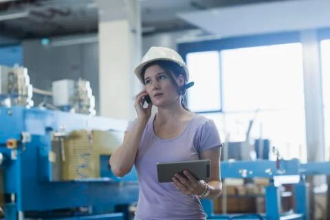 Female engineer using a digital tablet and mobile phone in an industrial plant Stock Photos