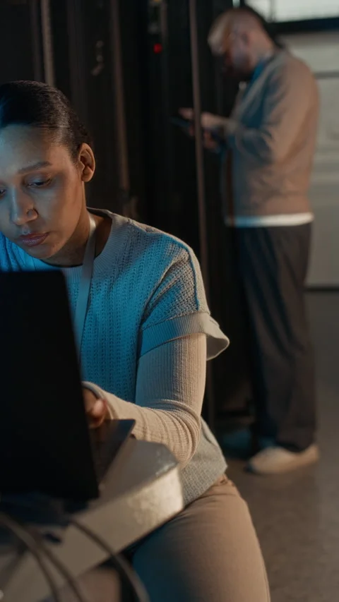 Female Engineer Using Laptop while Colleague Checking Network Server Panel Stock Footage 311311866
