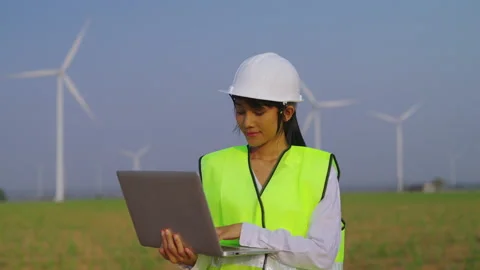 FEmale engineer using laptop at wind turbine farm. Video stock 235550531
