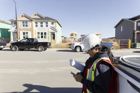 Female engineer using smart phone at sunny housing development Stockfoto's