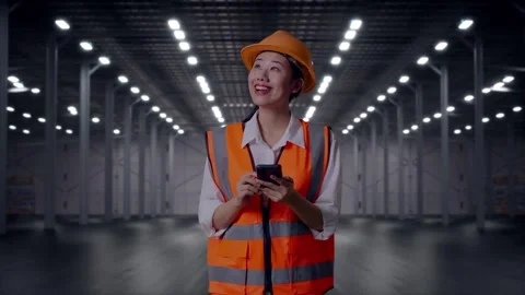 Female Engineer Using Smartphone in Empty Warehouse Stock Footage 318087166