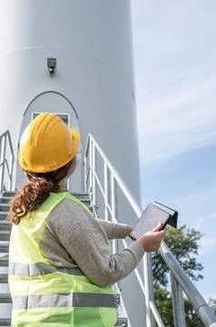 Female engineer using a tablet while wearing protective gear and a hard hat. Stock Photos