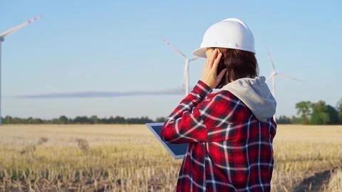 Female engineer wearing a white protective helmet is taking notes with a tablet 写真素材