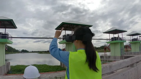 Female engineer wears VR glasses of virtual reality imagine future building dam. Stock Footage 156528131