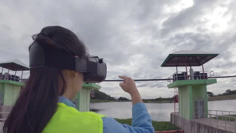 Female engineer wears VR glasses of virtual reality imagine future building dam. Stock Footage 156528147
