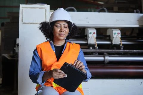 Female engineer worker quality control inspects by tablet at a paper factory. Stock Photos