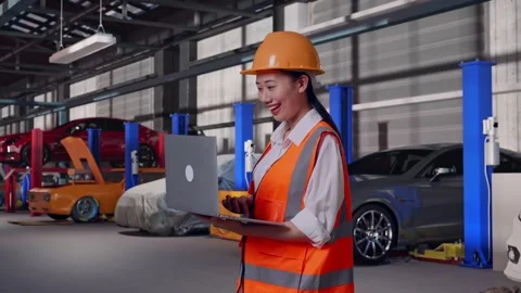 Female Engineer Working On A Laptop in Auto Repair Shop Stock Footage 313528293