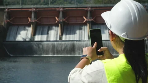Female engineer working with smartphone and looking away at dam Stock Footage 229709284