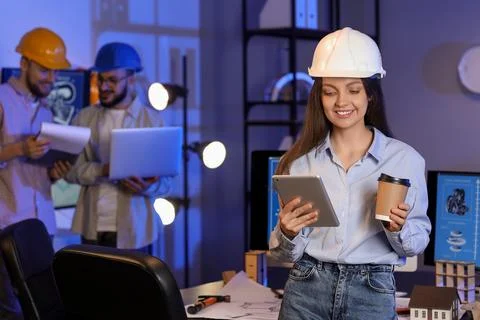 Female engineer working with tablet computer and coffee in office at night Stock Photos