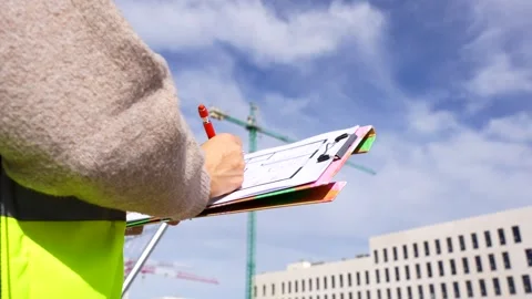 Female engineer writing on a clipboard at a construction site Stock Footage 334578647