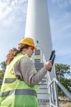 Female engineer with yellow helmet is using a digital tablet to inspect a w.. Foto stock