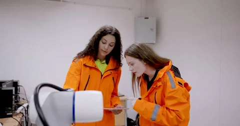 Female engineering trainer and female trainee reviewing robotic arm function Stock Footage 319475342