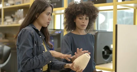Female engineers in creative office looking at 3d printer and model Stock Footage 165081882