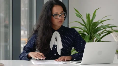 Female entrepreneur reading documents, analyzing financial papers, preparing Stock Footage 148320919