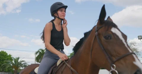 Female equestrian removing helmet while on her horse Stock Footage 107693470
