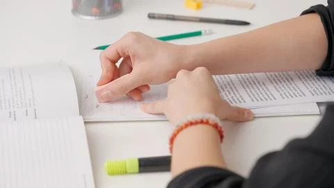 Female erasing wrong answer in standard exam test paper book with eraser Stock Photos