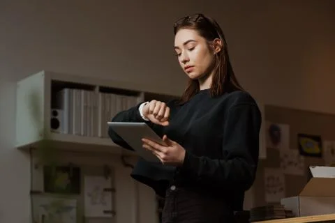 Female executive checking time while using digital tablet Foto stock