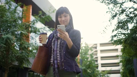 Female executive with coffee cup checking her phone outside office building Stock Footage 105623029