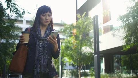 Female executive using her mobile phone while walking towards office building Stock Footage 105617564
