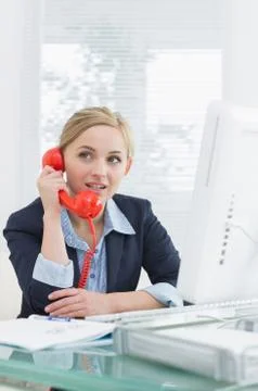 Female executive using red land line phone at desk Stock Photos