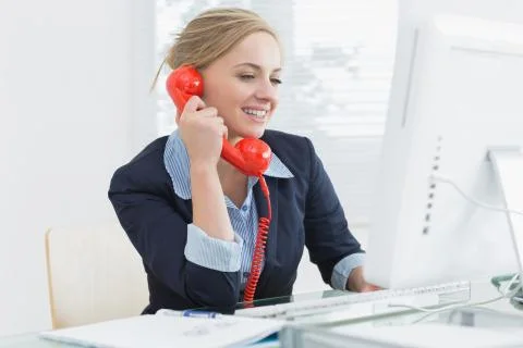 Female executive using red land line phone at desk Stock Photos