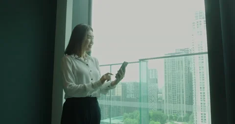 Female Executive Using Smart Phone at Window Looking out on City Stock Footage 197030635