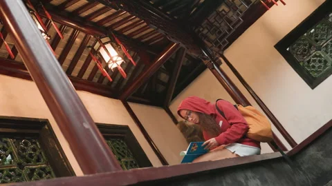 Female explorer immersed in cultural learning on wooden veranda. Heritage 動画素材 332787785