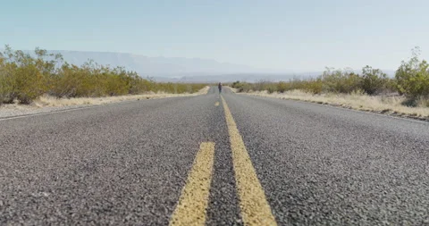 Female Explorer Walks Down Middle of Highway Stock Footage 238554338