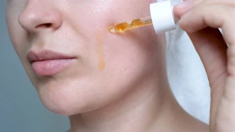 Female face and dropper with moisturizing serum close-up on a gray background. Stock Footage 200638371