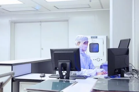 Female factory worker using computer in flexible electronics factory clean room Stock Photos