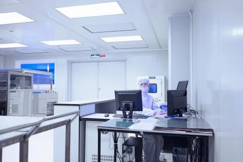 Female factory worker using computers in flexible electronics factory clean room Stock Photos