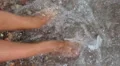 Female feet are washed by sea water HD Footage