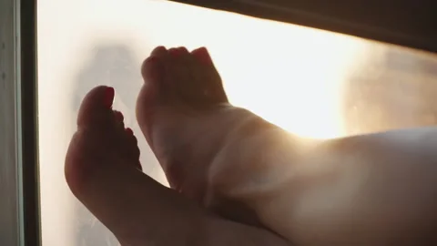 Female feet on the background of a window 스톡 동영상 167735907