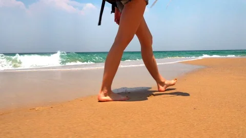 Female feet walk on the wet sand at the beach Stock Footage