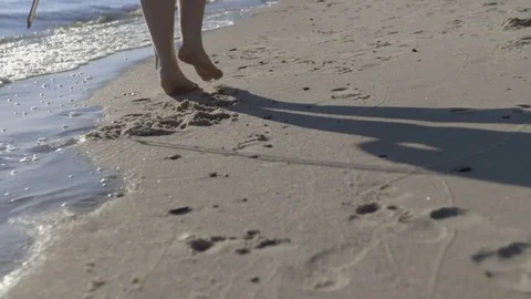 Female Feet Walking Barefoot on Sea Shore at Sunset. Slow Motion. Closeup. Stock Footage