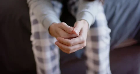 Female fidgeting hands on couch after loose clasp in plaid pants and sweatshirt, Stock Footage 339496182