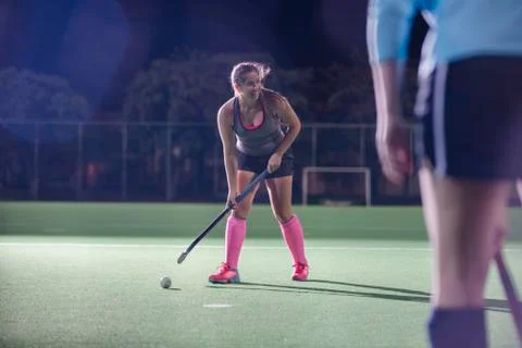 Female field hockey player hitting the ball with hockey stick on field Stock Photos