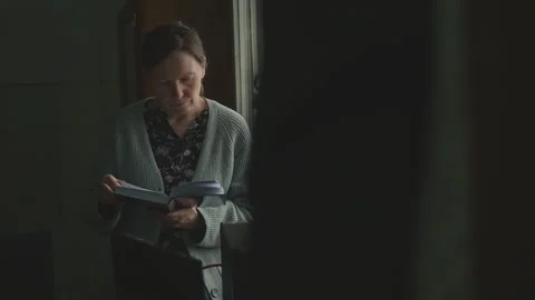 Female figure in low-lit old office room holding open book by the window, c.. Stock Footage 339765484