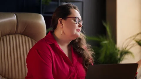 Female financial analyst reading documents and typing on laptop in the office Stock Footage 329769212