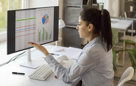 Female financial analyst working on data and charts at desktop computer in Stock Photos