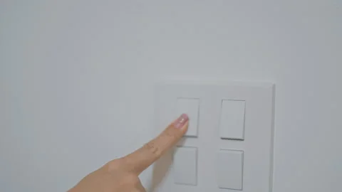 Female finger pushing for turn on light switch on white wall at home room. .. Stock Footage 313969784