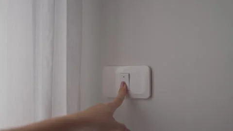 Female finger pushing for turn on light switch on white wall at home room. .. Stock Footage 334786575