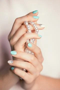 Female fingernails with turquoise white french diamond manicure and pearl Stock Photos