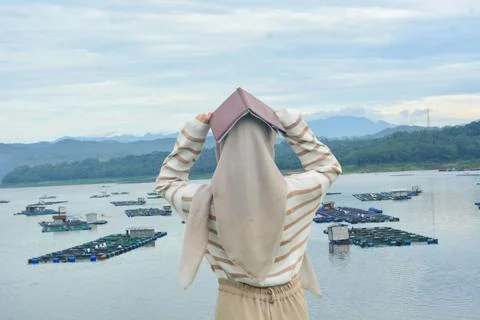 A female fish farm manager wears a safety vest and carries a book to check .. Stock Photos