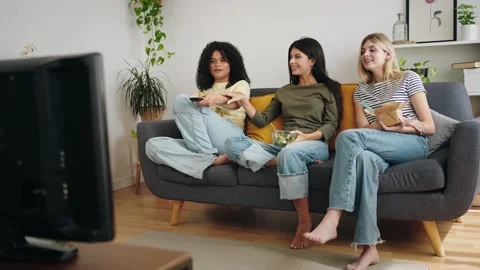 Female flatmate friends having fun at home watching television and eating meal Stock Footage 307020974
