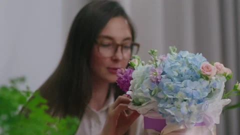 Female florist is customizing a beautiful box of flowers in a flower shop Stock Footage 195933184