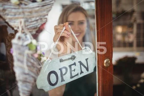 Female Florist Holding Open Signboard In The Flower Shop