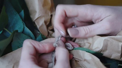 Female florist makes a bow from a thread on a bouquet for sale in a flower shop Stock Footage 86770432